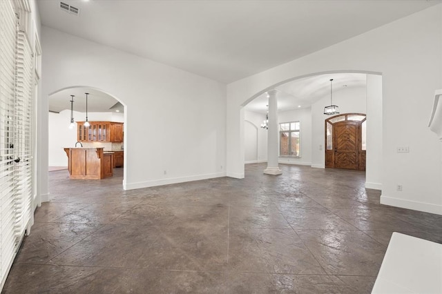 unfurnished living room featuring arched walkways, baseboards, and visible vents