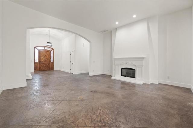 unfurnished living room with recessed lighting, arched walkways, finished concrete flooring, and baseboards