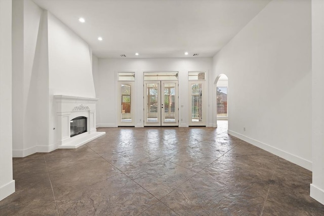 unfurnished living room featuring recessed lighting, a large fireplace, arched walkways, and baseboards