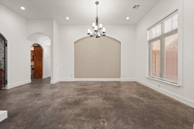 unfurnished dining area with visible vents, arched walkways, concrete flooring, baseboards, and a notable chandelier