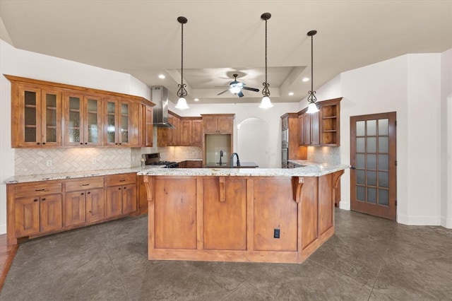 kitchen featuring wall chimney exhaust hood, a ceiling fan, open shelves, and brown cabinets