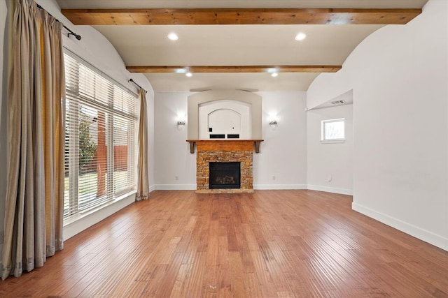unfurnished living room with baseboards, light wood-style floors, and beamed ceiling