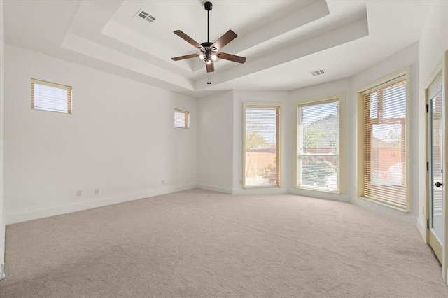 unfurnished room with a raised ceiling, visible vents, and light carpet