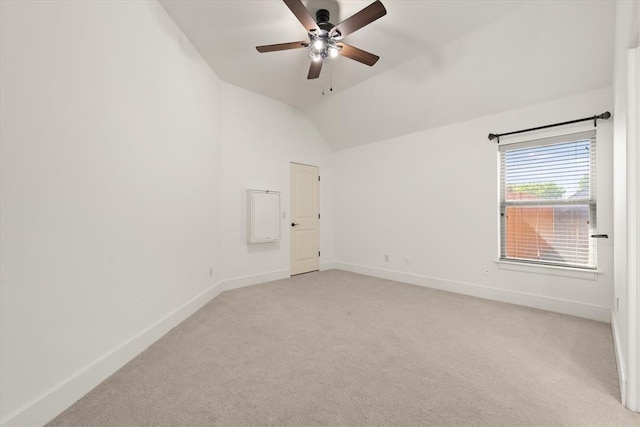 spare room featuring ceiling fan, vaulted ceiling, baseboards, and light colored carpet