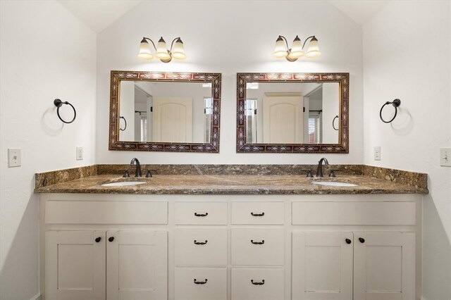 full bath featuring vaulted ceiling, a sink, and double vanity