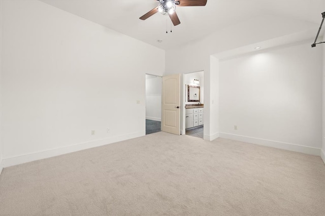 unfurnished bedroom with connected bathroom, ceiling fan, baseboards, light colored carpet, and lofted ceiling