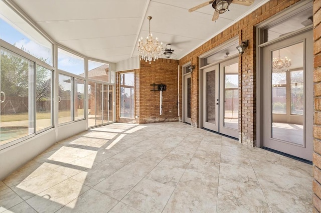 unfurnished sunroom featuring a healthy amount of sunlight, french doors, and ceiling fan with notable chandelier