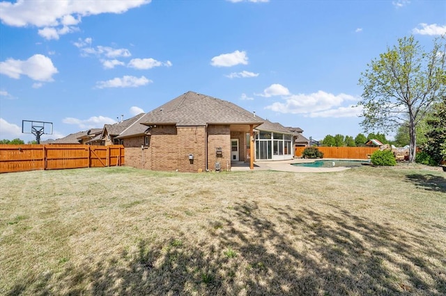 back of house with a fenced in pool, a fenced backyard, a yard, roof with shingles, and brick siding