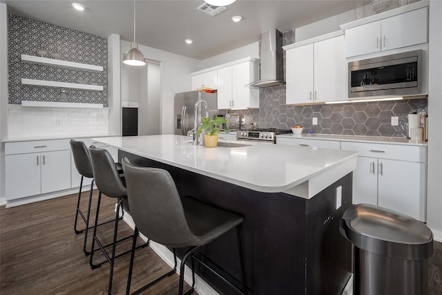kitchen with stainless steel appliances, visible vents, a kitchen bar, decorative backsplash, and wall chimney range hood