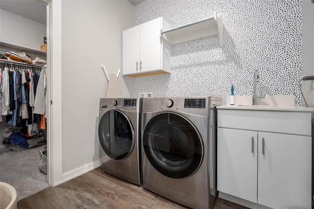 laundry area featuring a sink, baseboards, separate washer and dryer, wood finished floors, and cabinet space