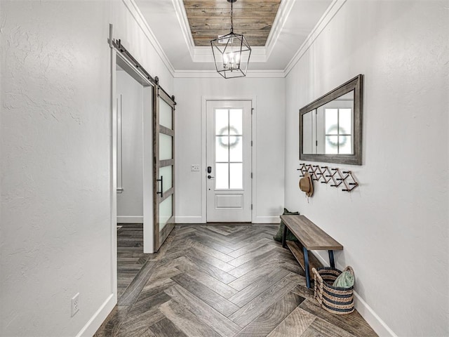 entryway with a barn door, a notable chandelier, a tray ceiling, crown molding, and baseboards