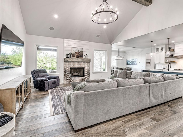living area with wood finished floors, high vaulted ceiling, a notable chandelier, and recessed lighting