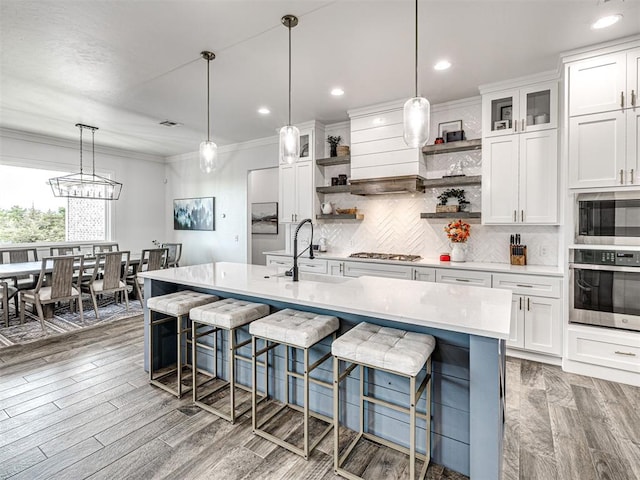 kitchen with open shelves, white cabinets, a sink, appliances with stainless steel finishes, and light countertops