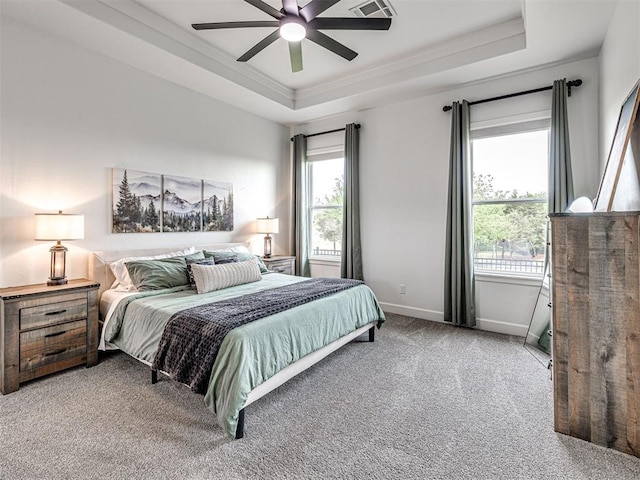 carpeted bedroom featuring crown molding, a tray ceiling, a ceiling fan, and baseboards