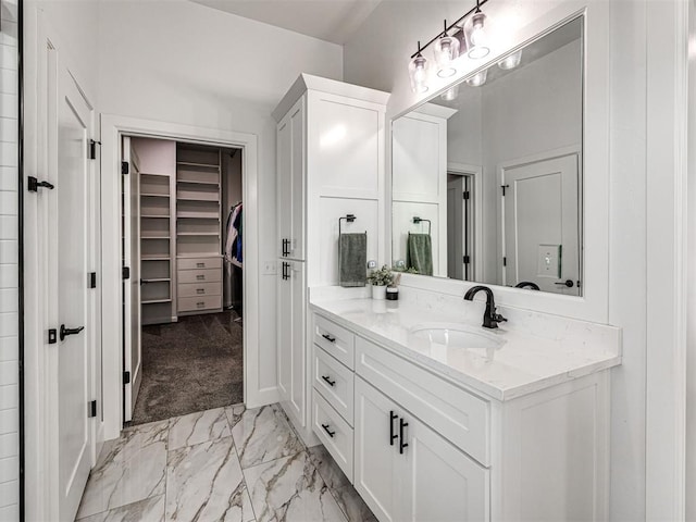 full bathroom featuring marble finish floor, vanity, and a spacious closet