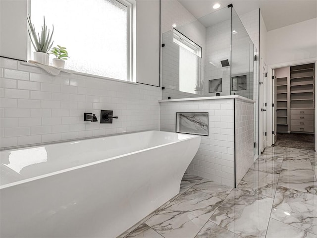 full bathroom featuring marble finish floor, tiled shower, a soaking tub, and a fireplace