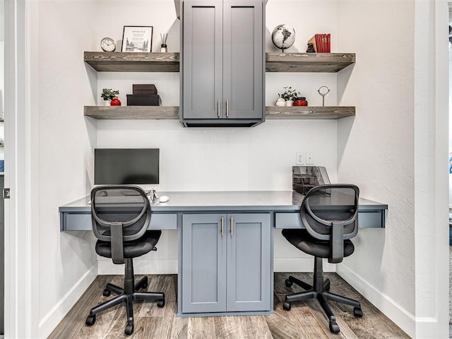 office space featuring wood finished floors, baseboards, and built in study area