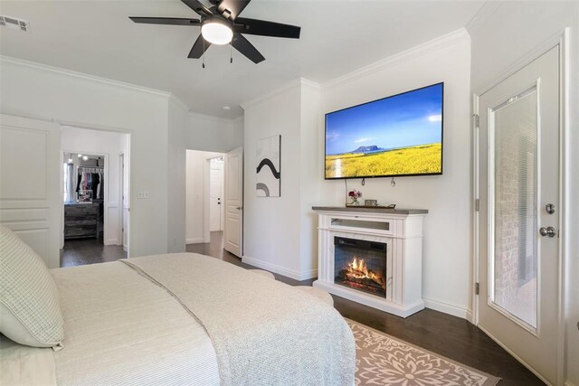 2201 Pine View Ter, Edmond, OK 73003 - bedroom with dark wood-style flooring, ornamental molding, a glass covered fireplace, baseboards, and a ceiling fan