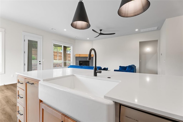 kitchen featuring light wood-type flooring, open floor plan, light countertops, a ceiling fan, and a sink