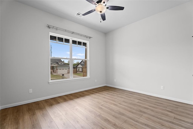 empty room with wood finished floors, ceiling fan, baseboards, and visible vents