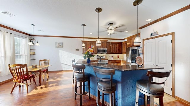 130 Quail Dr, Healdton, OK 73438 - kitchen with ornamental molding, appliances with stainless steel finishes, a kitchen breakfast bar, and a ceiling fan