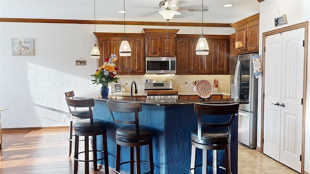 130 Quail Dr, Healdton, OK 73438 - kitchen with a kitchen breakfast bar, stainless steel appliances, backsplash, a ceiling fan, and decorative light fixtures