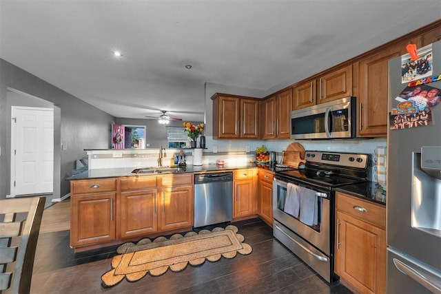 7909 Chumley Ln, Oklahoma City, OK 73135 - kitchen featuring brown cabinets, a sink, stainless steel appliances, a ceiling fan, and a peninsula