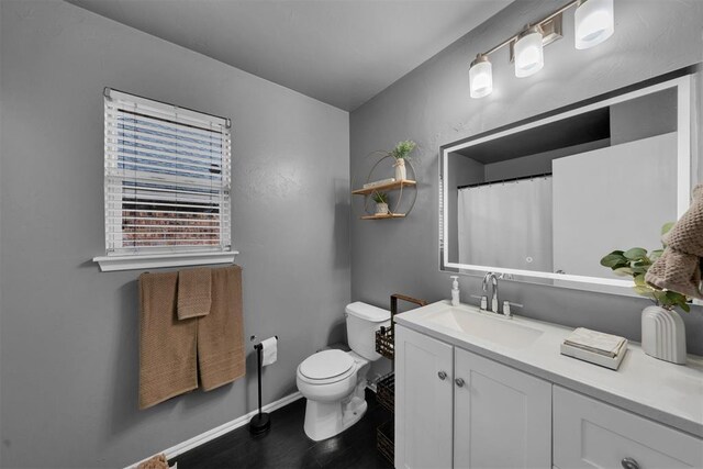 7909 Chumley Ln, Oklahoma City, OK 73135 - full bath featuring wood finished floors, vanity, baseboards, toilet, and a shower with shower curtain