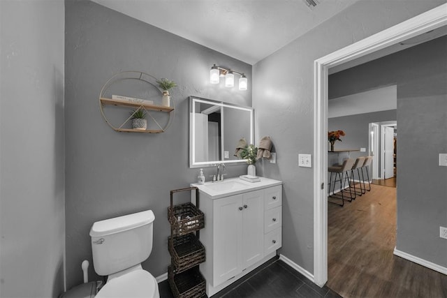 7909 Chumley Ln, Oklahoma City, OK 73135 - bathroom with baseboards, wood finished floors, toilet, and vanity
