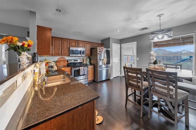 7909 Chumley Ln, Oklahoma City, OK 73135 - kitchen with visible vents, dark wood-type flooring, brown cabinets, a sink, and stainless steel appliances