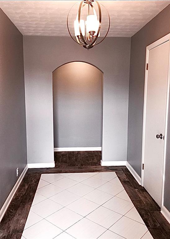 503 Kingston Dr, Yukon, OK 73099 - spare room featuring arched walkways, wood finished floors, baseboards, and a notable chandelier