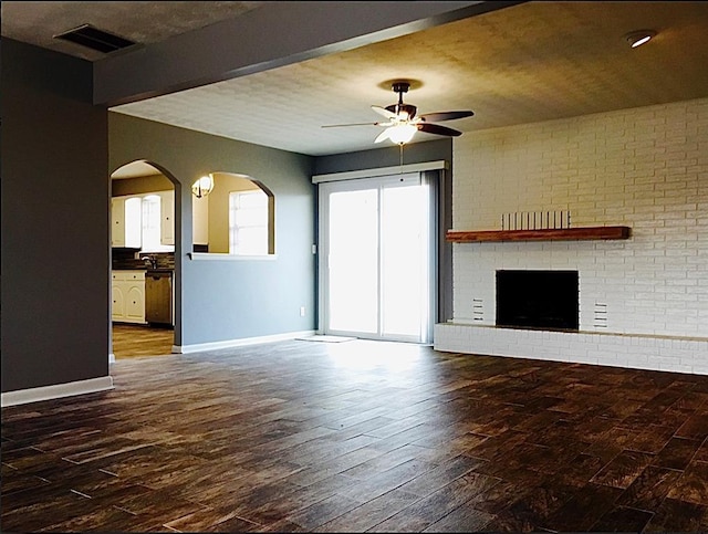 503 Kingston Dr, Yukon, OK 73099 - unfurnished living room with a ceiling fan, hardwood / wood-style floors, baseboards, a brick fireplace, and visible vents