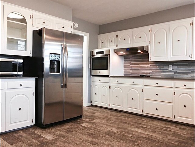 503 Kingston Dr, Yukon, OK 73099 - kitchen with dark wood-style flooring, dark countertops, appliances with stainless steel finishes, white cabinets, and under cabinet range hood