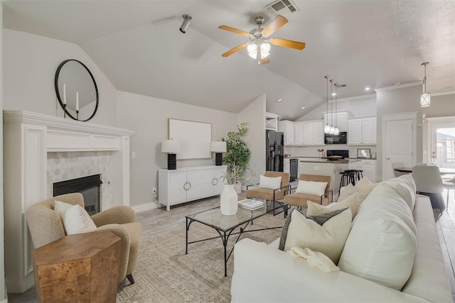 15924 Sky Run Dr, Edmond, OK 73013 - living room with ceiling fan, a fireplace, lofted ceiling, light wood-type flooring, and visible vents