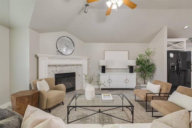 15924 Sky Run Dr, Edmond, OK 73013 - living area featuring ceiling fan, a tiled fireplace, vaulted ceiling, wood finished floors, and baseboards