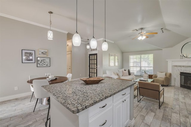 15924 Sky Run Dr, Edmond, OK 73013 - kitchen featuring a ceiling fan, a center island, a fireplace, white cabinets, and light wood finished floors