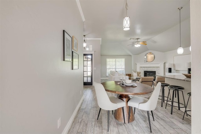 15924 Sky Run Dr, Edmond, OK 73013 - dining room with ceiling fan, light wood-style floors, a glass covered fireplace, baseboards, and vaulted ceiling