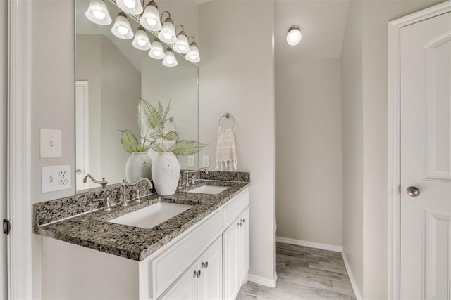 15924 Sky Run Dr, Edmond, OK 73013 - bathroom with double vanity, a sink, baseboards, and wood finished floors