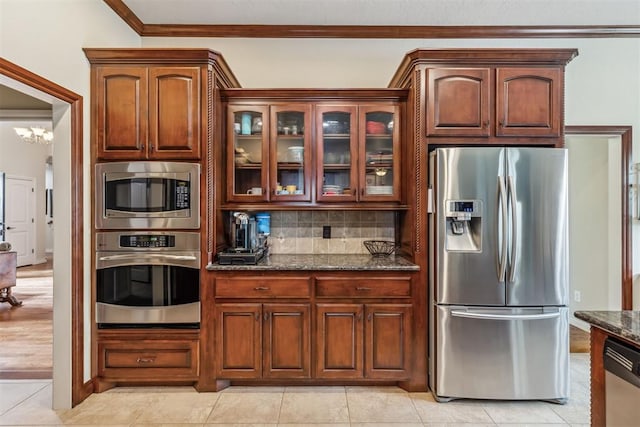 4608 Greystone Ct, Norman, OK 73072 - kitchen featuring dark stone counters, crown molding, glass insert cabinets, backsplash, and appliances with stainless steel finishes