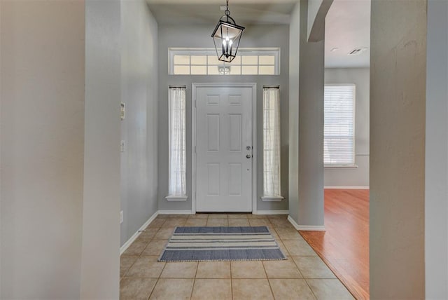 tiled foyer entrance featuring baseboards, visible vents, and arched walkways