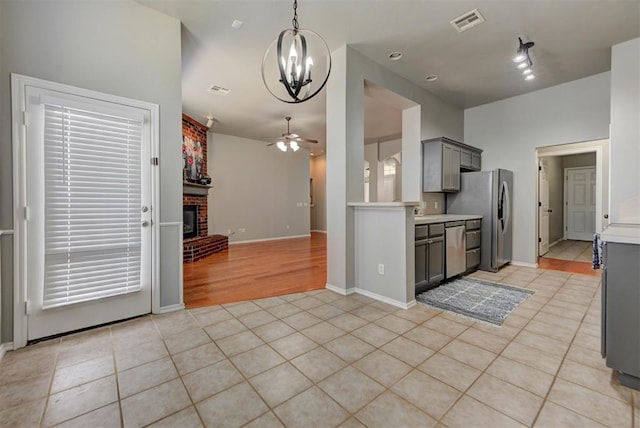 kitchen with ceiling fan with notable chandelier, light tile patterned flooring, stainless steel appliances, gray cabinetry, and visible vents