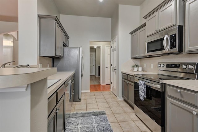 kitchen featuring gray cabinets, appliances with stainless steel finishes, light countertops, and light tile patterned floors