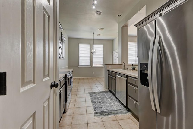 kitchen featuring a sink, light tile patterned flooring, stainless steel appliances, light countertops, and visible vents