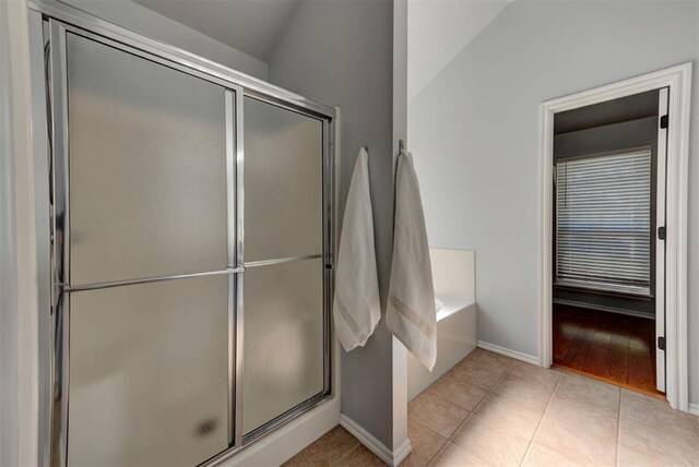 bathroom featuring a bath, tile patterned floors, baseboards, and a stall shower