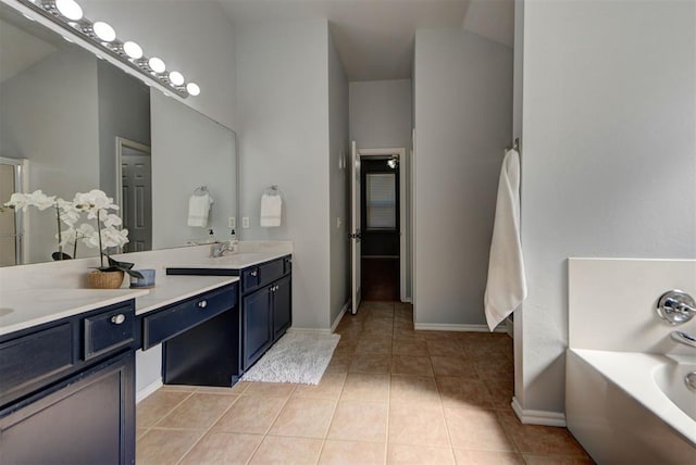 bathroom with baseboards, a garden tub, tile patterned flooring, and vanity