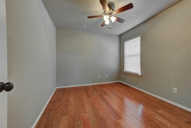 spare room with ceiling fan, baseboards, wood finished floors, and visible vents