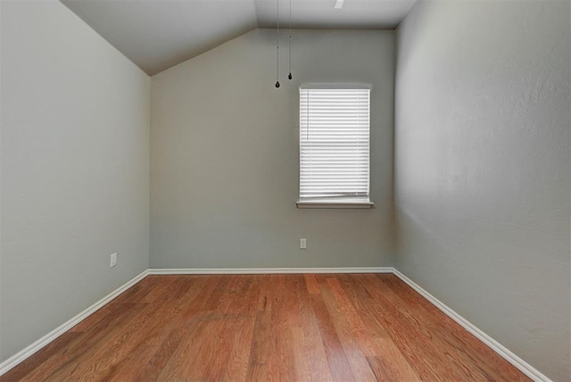 additional living space with baseboards, vaulted ceiling, and wood finished floors