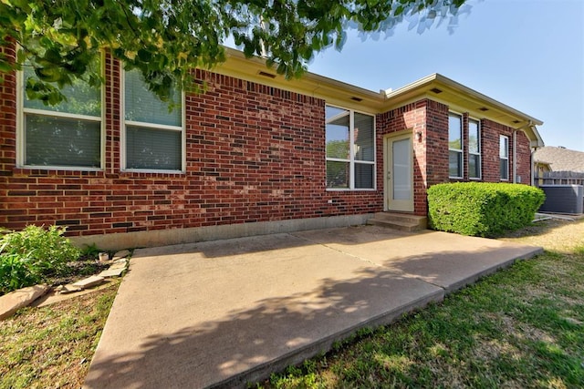 view of front of house with brick siding, a patio area, and cooling unit