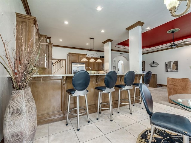 8016 NW 124th St, Oklahoma City, OK 73142 - kitchen featuring a peninsula, stainless steel fridge, light tile patterned floors, a breakfast bar, and brown cabinets
