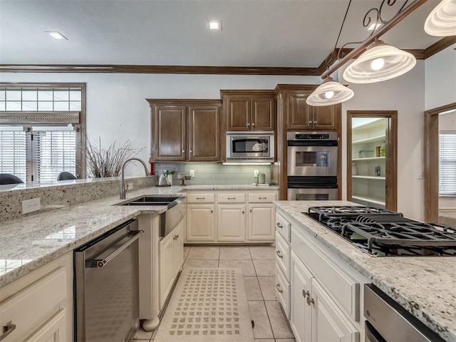 8016 NW 124th St, Oklahoma City, OK 73142 - kitchen featuring appliances with stainless steel finishes, crown molding, a sink, tasteful backsplash, and light stone countertops